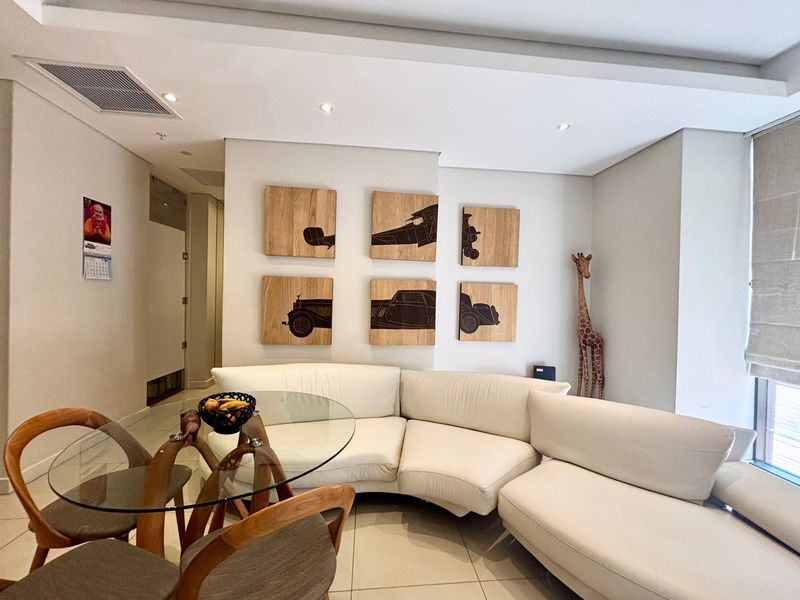 A bright and modern living area featuring tiled flooring, recessed downlighting, and integrated ducted air conditioning, offering a clean and well-maintained space.