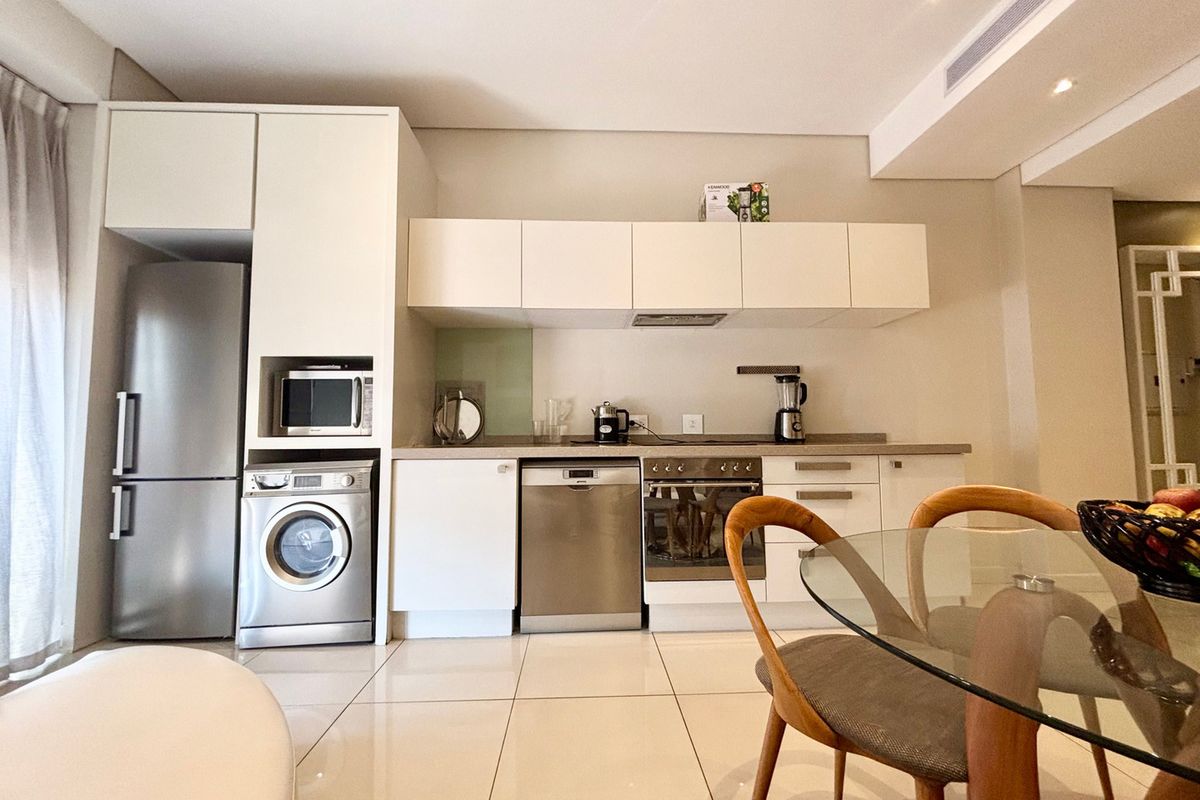 Modern kitchen featuring sleek white cabinetry, integrated stainless steel appliances, and polished tiled flooring in an open-plan layout.