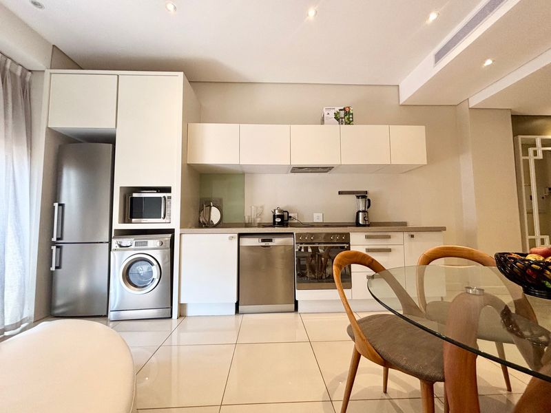 Modern kitchen featuring sleek white cabinetry, integrated stainless steel appliances, and polished tiled flooring in an open-plan layout.