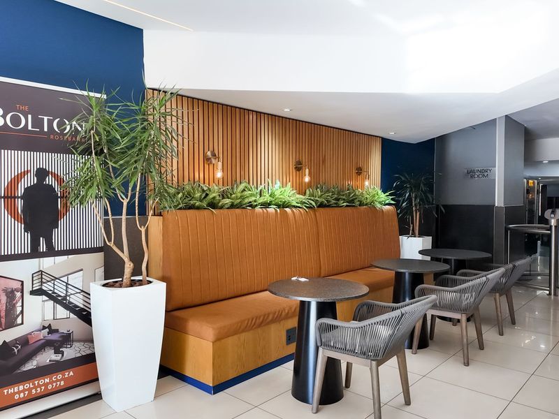 A modern, well-maintained communal clubhouse area featuring stylish slatted timber wall paneling, built-in banquette seating, and polished floor tiles.