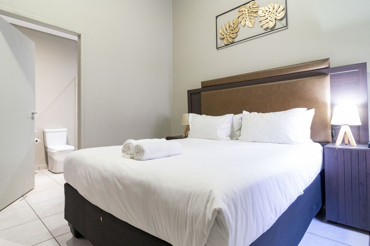 A well-maintained bedroom featuring tiled flooring and direct access to an en-suite bathroom.
