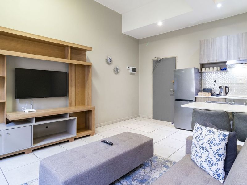 Open-plan living area featuring a modern kitchen with built-in cabinetry, tiled flooring, and recessed lighting, seamlessly connected to the lounge space.