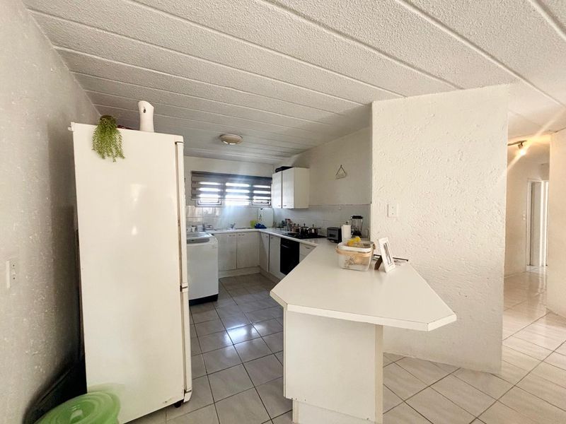 Functional kitchen featuring white cabinetry, tiled flooring, a breakfast bar, and integrated cooking appliances, offering a practical layout for daily meal preparation.