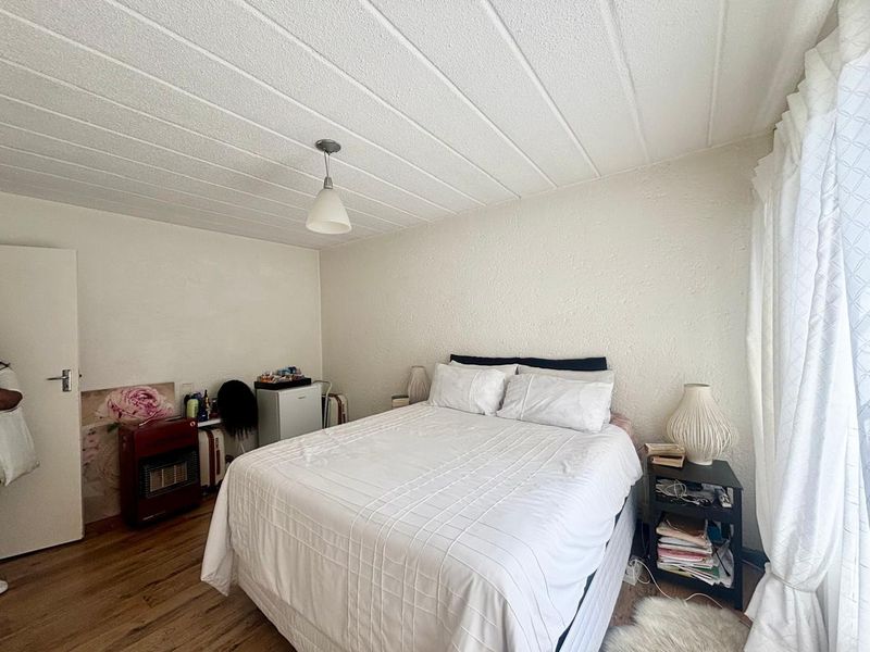 A bedroom featuring laminate flooring and a textured ceiling, requiring cosmetic updates to improve the overall finish and appeal.