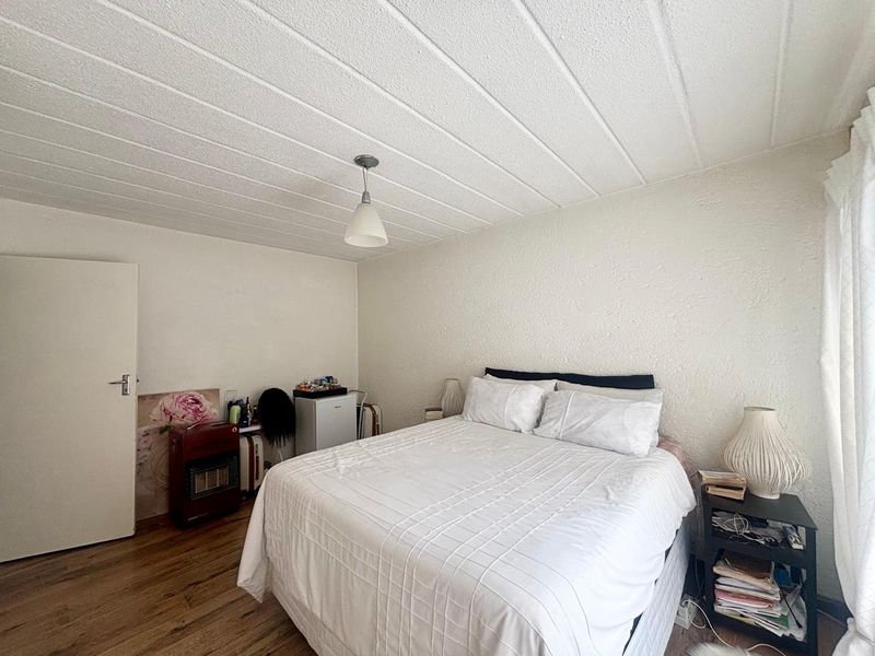 A bedroom featuring laminate flooring and a textured ceiling, providing a functional space with neutral finishes.