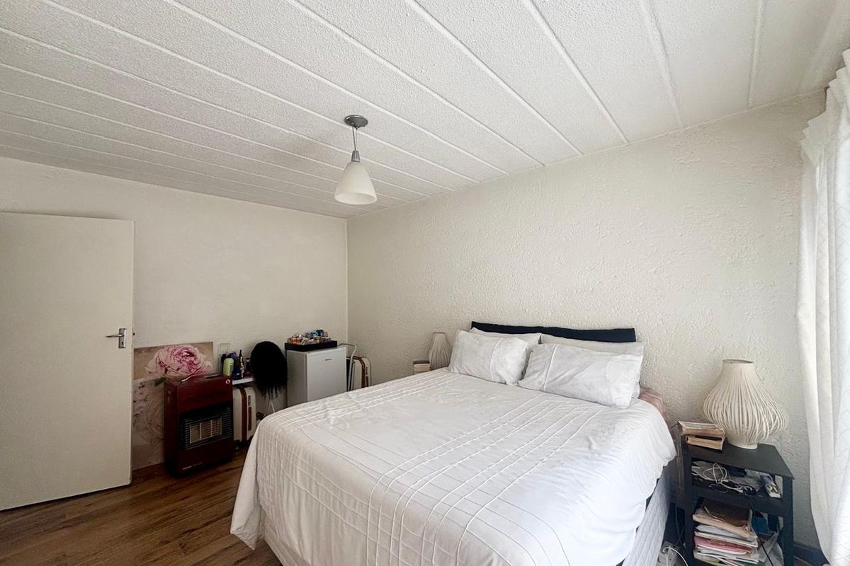 A bedroom featuring laminate flooring and a textured ceiling, providing a functional space with neutral finishes.