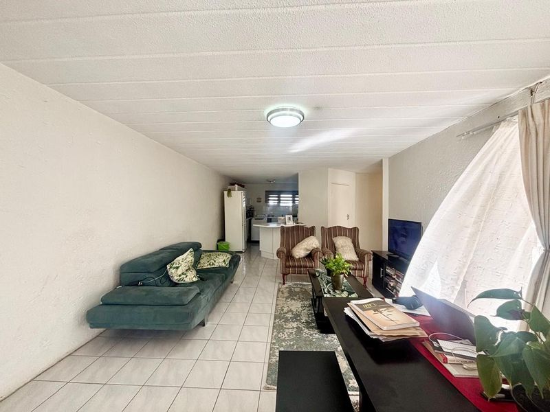 Open plan living area featuring tiled flooring and a functional kitchen space with a breakfast counter, offering a versatile layout for modern apartment living.