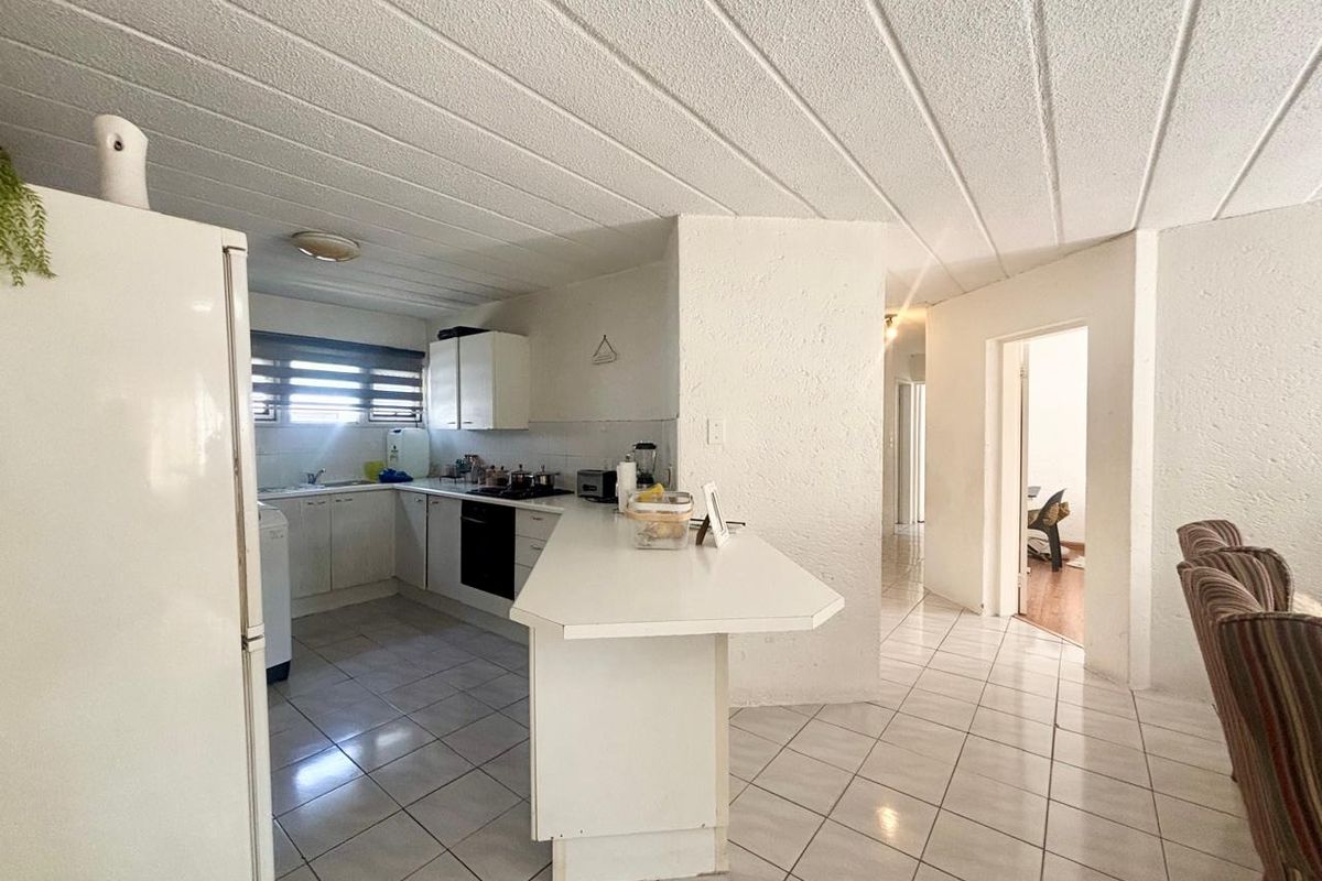Functional kitchen featuring white cabinetry, a breakfast bar, and ceramic tile flooring, offering a practical layout with potential for modern updates.