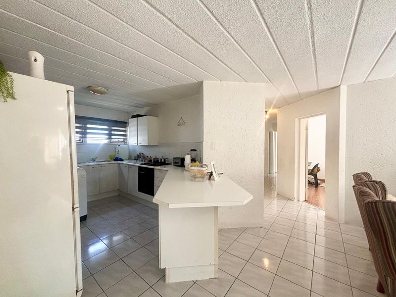Functional kitchen featuring white cabinetry, a breakfast bar, and ceramic tile flooring, offering a practical layout with potential for modern updates.