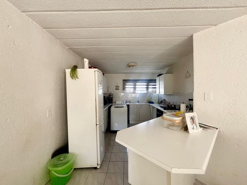 A functional kitchen featuring built-in cabinetry, a breakfast bar, and tiled flooring, offering a practical layout with potential for modern updates.