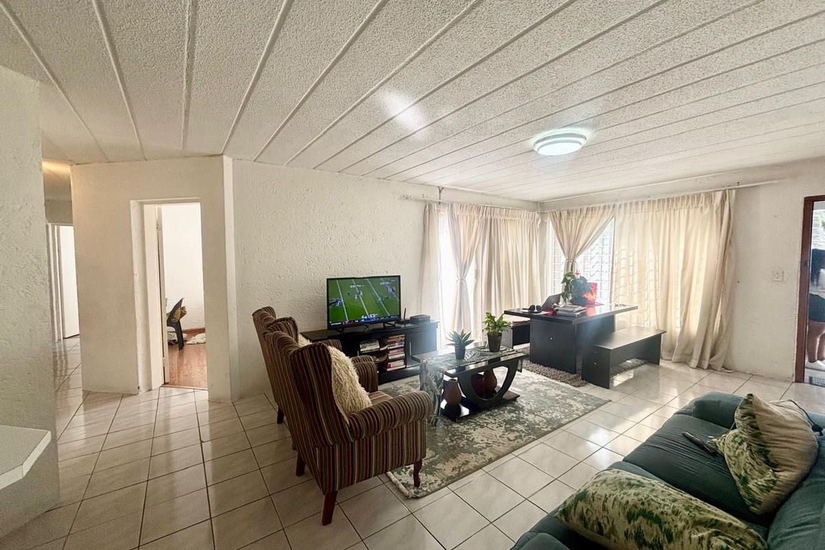 Spacious living area featuring tiled flooring and a textured ceiling, with direct access to an outdoor space through sliding glass doors.