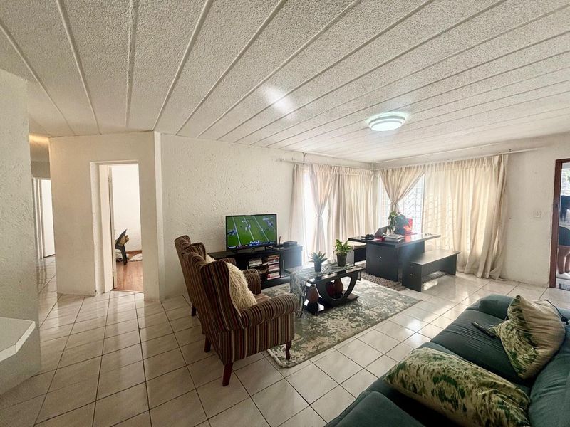 Spacious living area featuring tiled flooring and a textured ceiling, with direct access to an outdoor space through sliding glass doors.