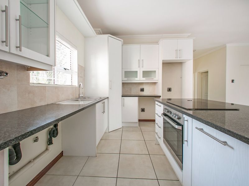 Modern kitchen featuring white cabinetry, granite countertops, built-in oven, electric hob, and tiled flooring, offering a clean and functional workspace.