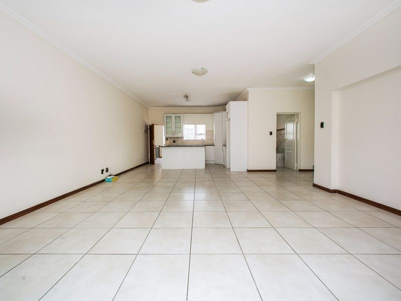 Spacious open-plan living area featuring neutral tiled flooring and a functional kitchen with built-in cabinetry and island.