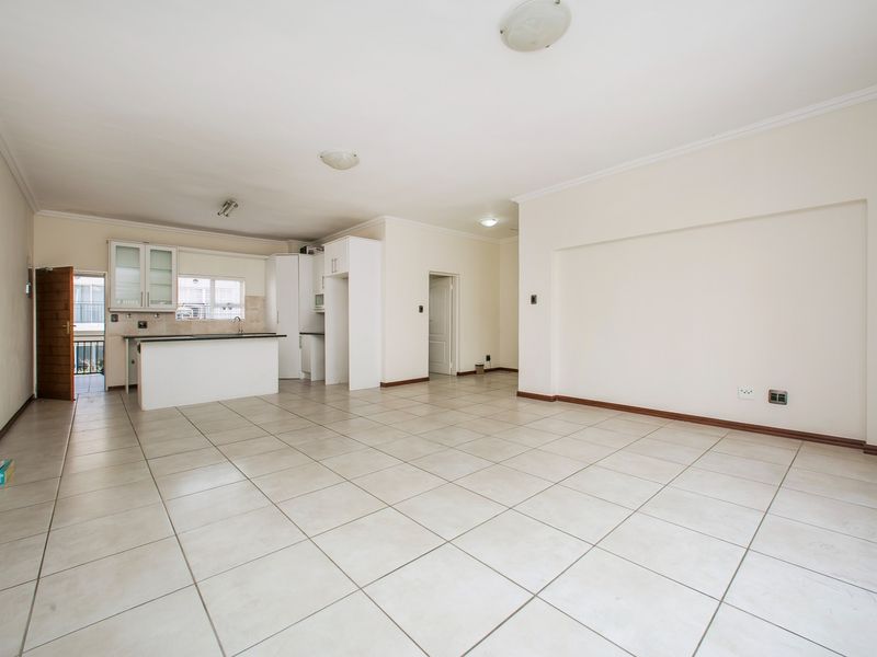 Spacious open-plan living area featuring tiled flooring and a functional kitchen with built-in cabinetry and a breakfast island.