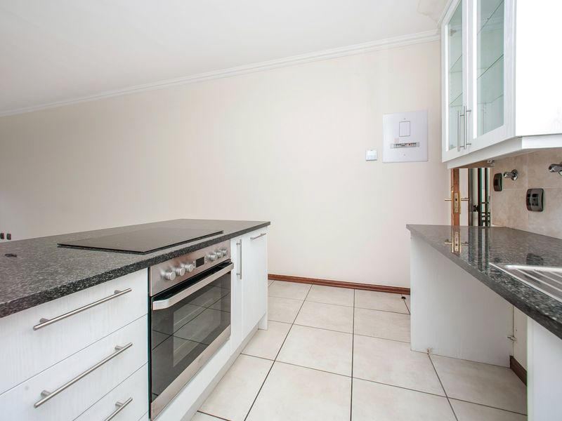 A functional kitchen featuring granite countertops, built-in oven and hob, and ample cabinetry, providing a clean and practical workspace.