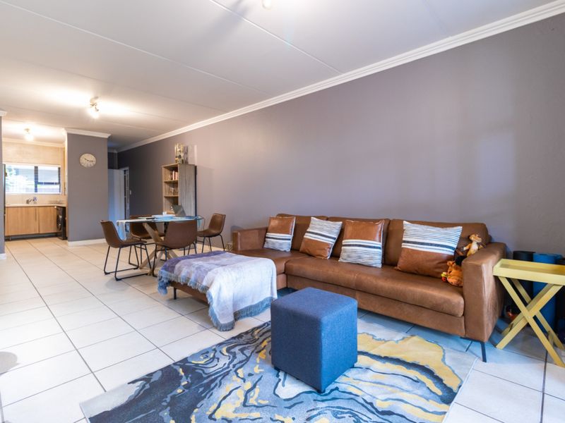 Open-plan living and dining area featuring tiled flooring, crown molding, and a connected kitchen space with built-in cabinetry.