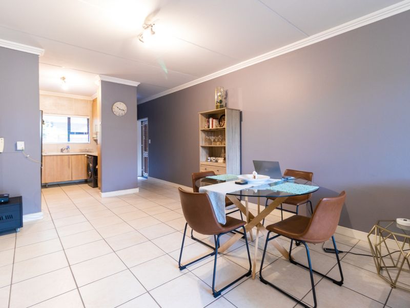 Open plan living and dining area featuring tiled flooring, crown molding, and an adjacent kitchen space with built-in cabinetry.
