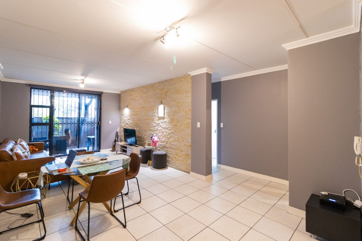 Spacious living area featuring a textured stone accent wall, neutral tiled flooring, and sliding glass doors leading to an outdoor space.