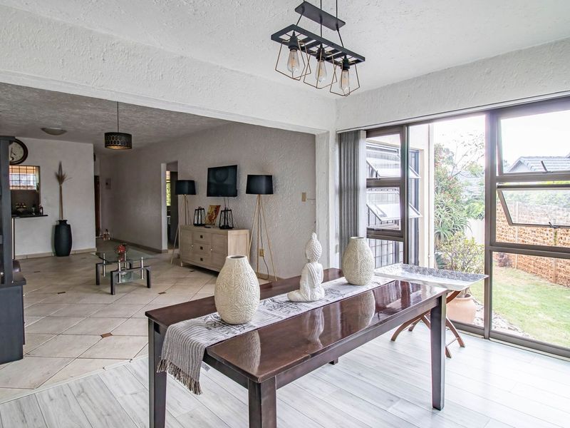 Spacious open-plan living and dining area featuring a mix of tiled and laminate flooring with large sliding glass doors providing access to the garden.