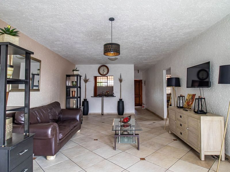 Spacious living room featuring textured ceilings, ceramic tiled flooring, and a convenient pass-through window connecting to the adjacent area.