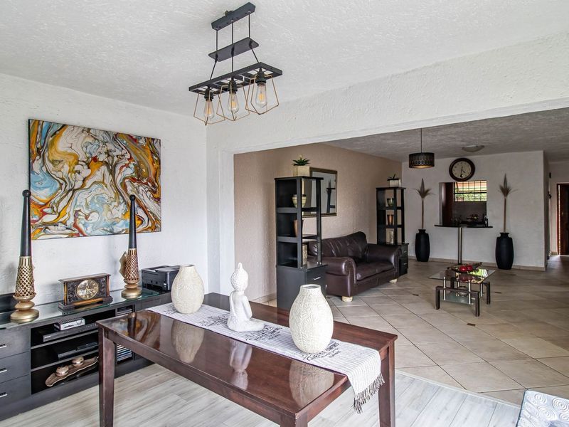 Spacious open-plan living and dining area featuring a mix of tiled and laminate flooring with modern pendant lighting and textured wall finishes.