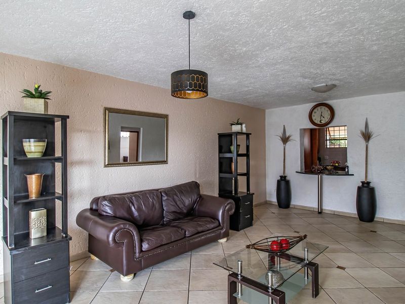 A living room featuring ceramic tile flooring, textured walls, and a convenient pass-through window with a built-in breakfast bar.