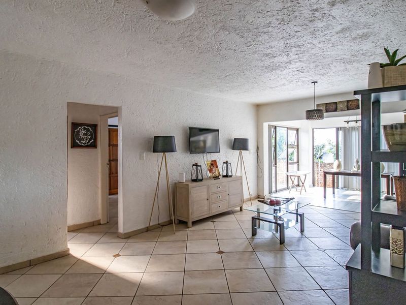 Spacious living area featuring textured walls, ceramic floor tiles, and large sliding glass doors providing access to an outdoor patio space.