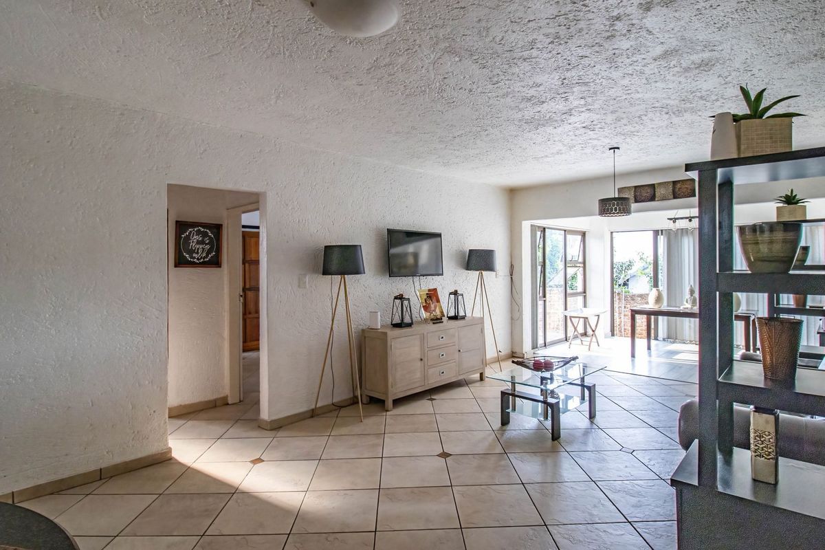 Spacious living area featuring textured walls, ceramic floor tiles, and large sliding glass doors providing access to an outdoor patio space.