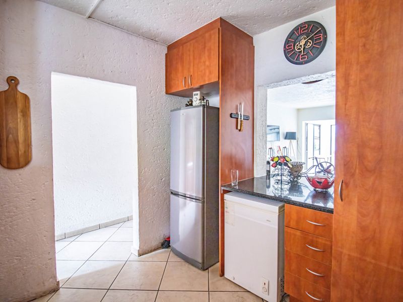 A compact kitchen area featuring built-in wooden cabinetry, granite countertops, and tiled flooring, with a convenient pass-through window to the adjacent living space.