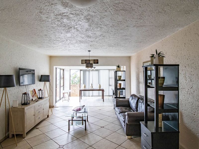 Spacious open-plan living area featuring tiled flooring, textured walls, and large sliding glass doors leading to an outdoor space.