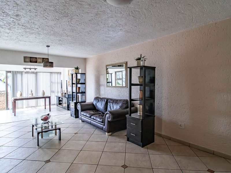 Spacious open-plan living area featuring tiled flooring, textured ceilings, and large sliding glass doors that provide ample natural light.