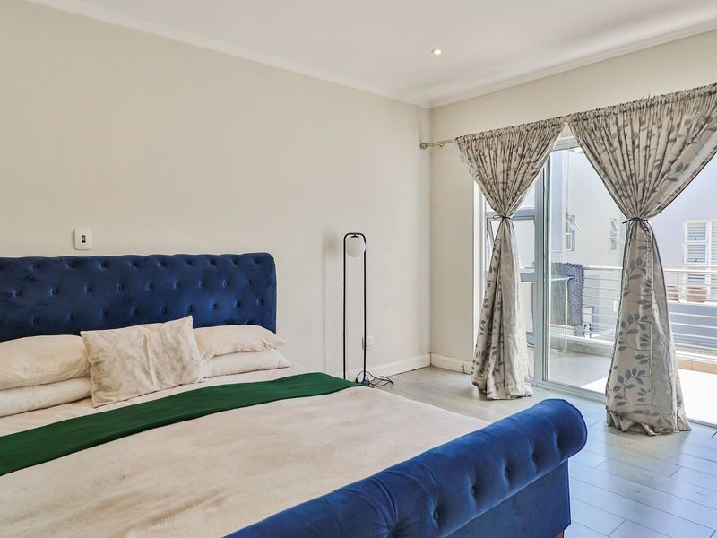 Spacious bedroom featuring neutral walls, laminate flooring, and a large sliding glass door providing direct access to a private balcony.