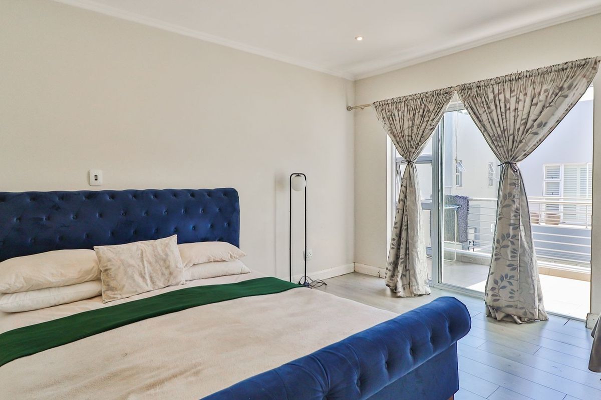 Spacious bedroom featuring neutral walls, laminate flooring, and a large sliding glass door providing direct access to a private balcony.