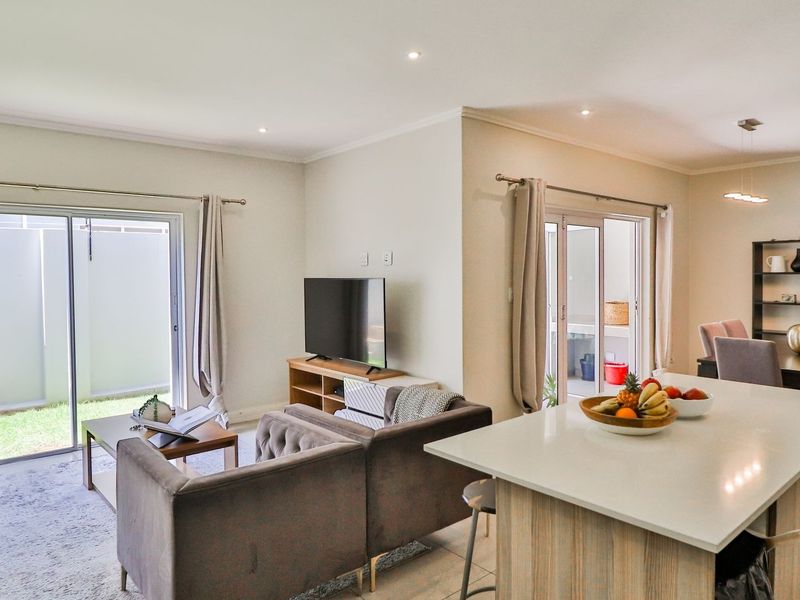 Spacious open-plan living and dining area featuring a modern kitchen island, tiled floors, and large sliding doors providing seamless access to the outdoor space.