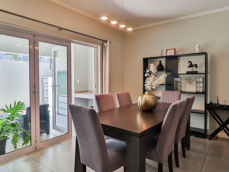 A bright dining area featuring tiled floors and double glass doors that provide seamless access to the outdoor patio space.