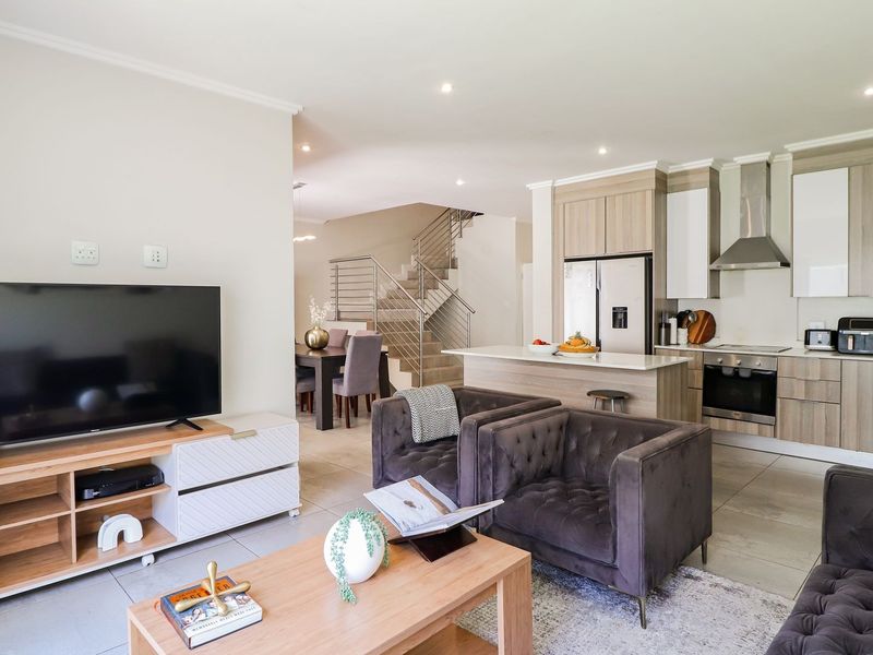 Spacious open-plan living area featuring a modern kitchen with built-in cabinetry, a central island, and a staircase leading to the upper level.