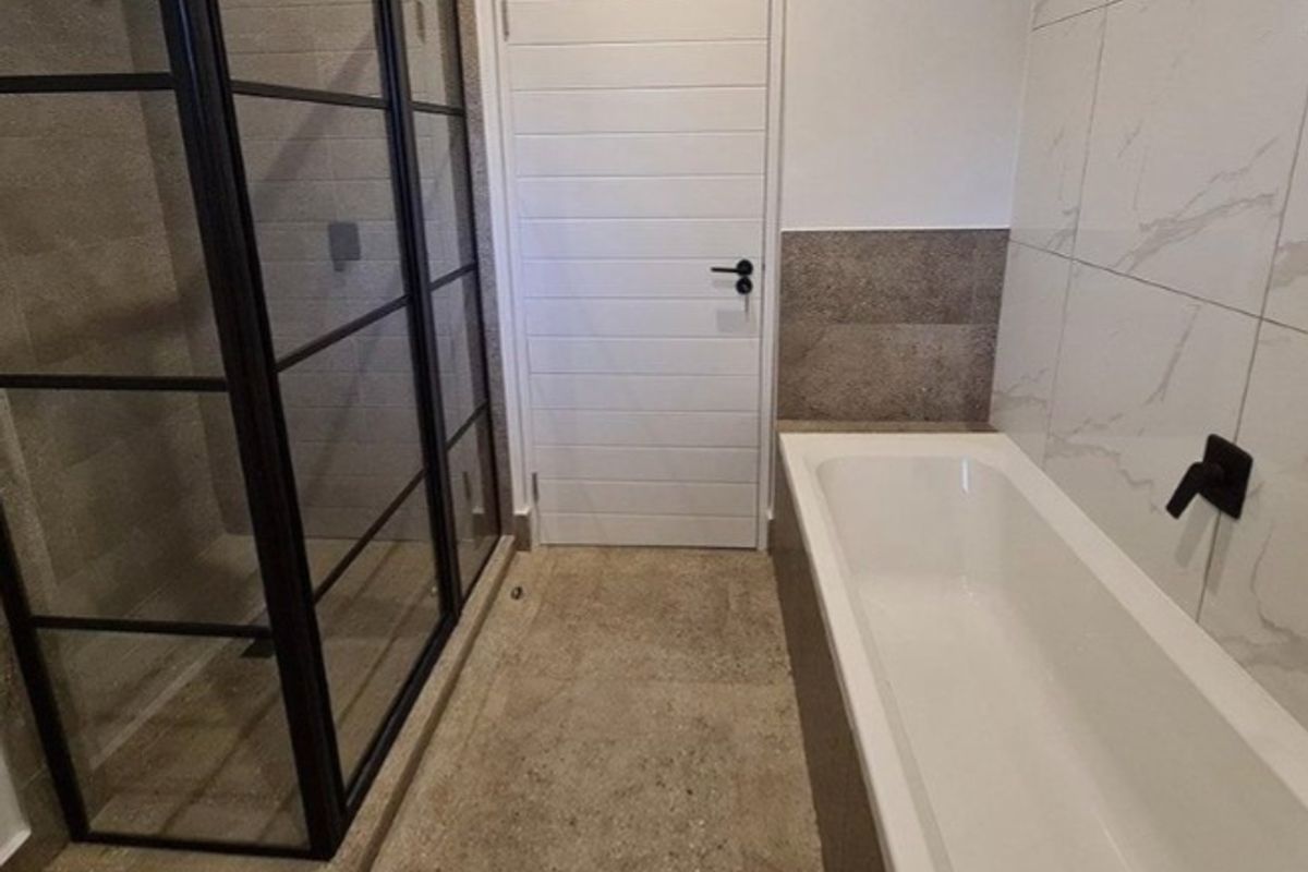 Modern bathroom featuring a walk-in shower with black-framed glass, a built-in bathtub with wall-mounted fixtures, and contemporary marble-effect wall tiling.