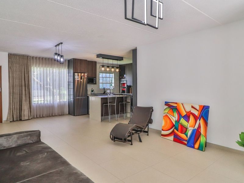 Spacious open-plan living area featuring a modern kitchen with a central island, tiled flooring, and neutral finishes throughout.