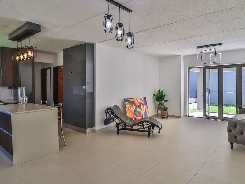 Modern open-plan living area featuring a contemporary kitchen with an island, sleek cabinetry, and large sliding doors leading to an outdoor space.