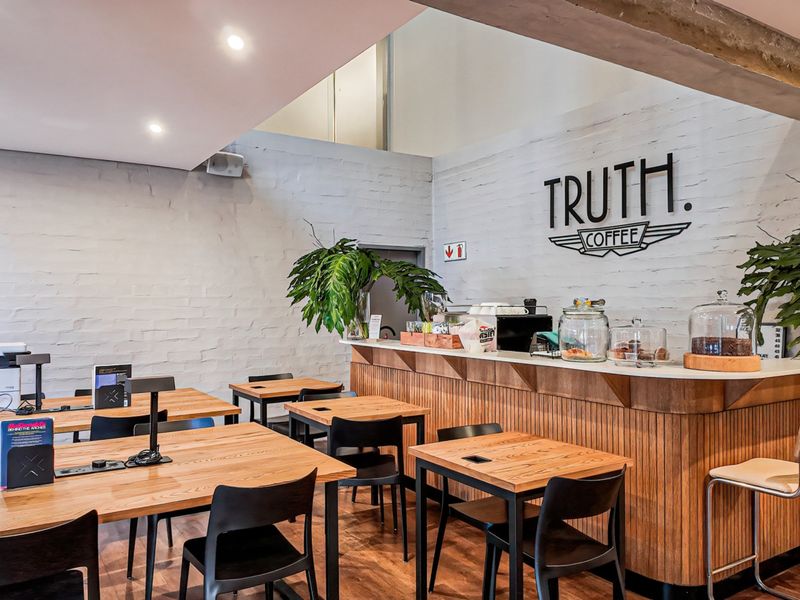 Open plan commercial space featuring a built-in service counter, exposed brick walls, recessed lighting, and timber flooring.
