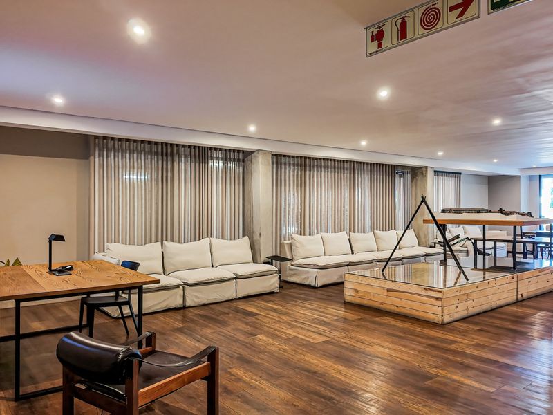 Spacious living area featuring warm timber flooring, exposed concrete structural columns, and recessed downlighting, creating a modern and open atmosphere.