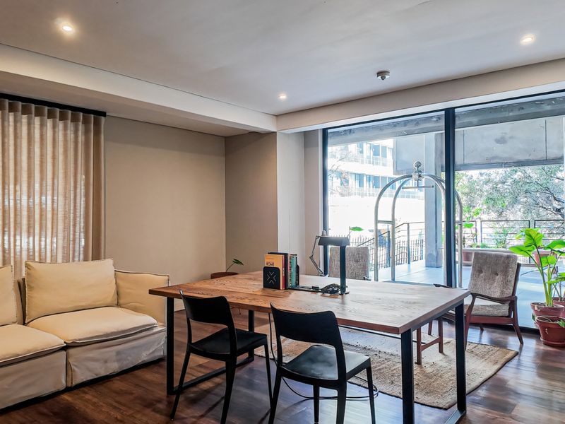 A bright living area featuring hardwood flooring, recessed lighting, and large sliding glass doors that open onto a private balcony.