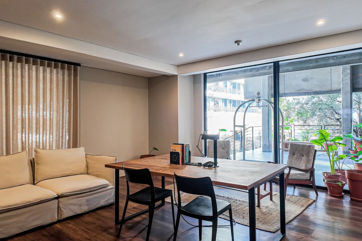 A bright living area featuring hardwood flooring, recessed lighting, and large sliding glass doors that open onto a private balcony.