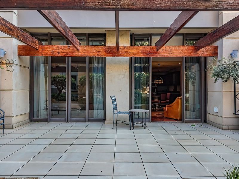 A spacious covered patio featuring a timber pergola, tiled flooring, and large sliding glass doors providing seamless access to the interior living space.