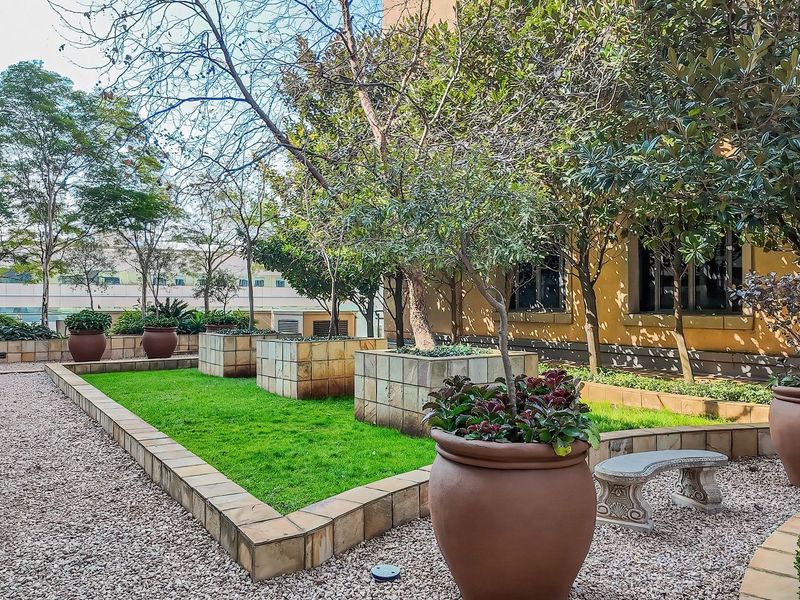 A well-maintained landscaped garden area featuring raised stone planters, gravel pathways, and established trees, providing a pleasant outdoor space.