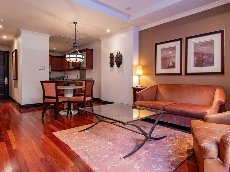 Open-plan living and dining area featuring rich hardwood flooring, recessed lighting, and an integrated kitchen with dark wood cabinetry.