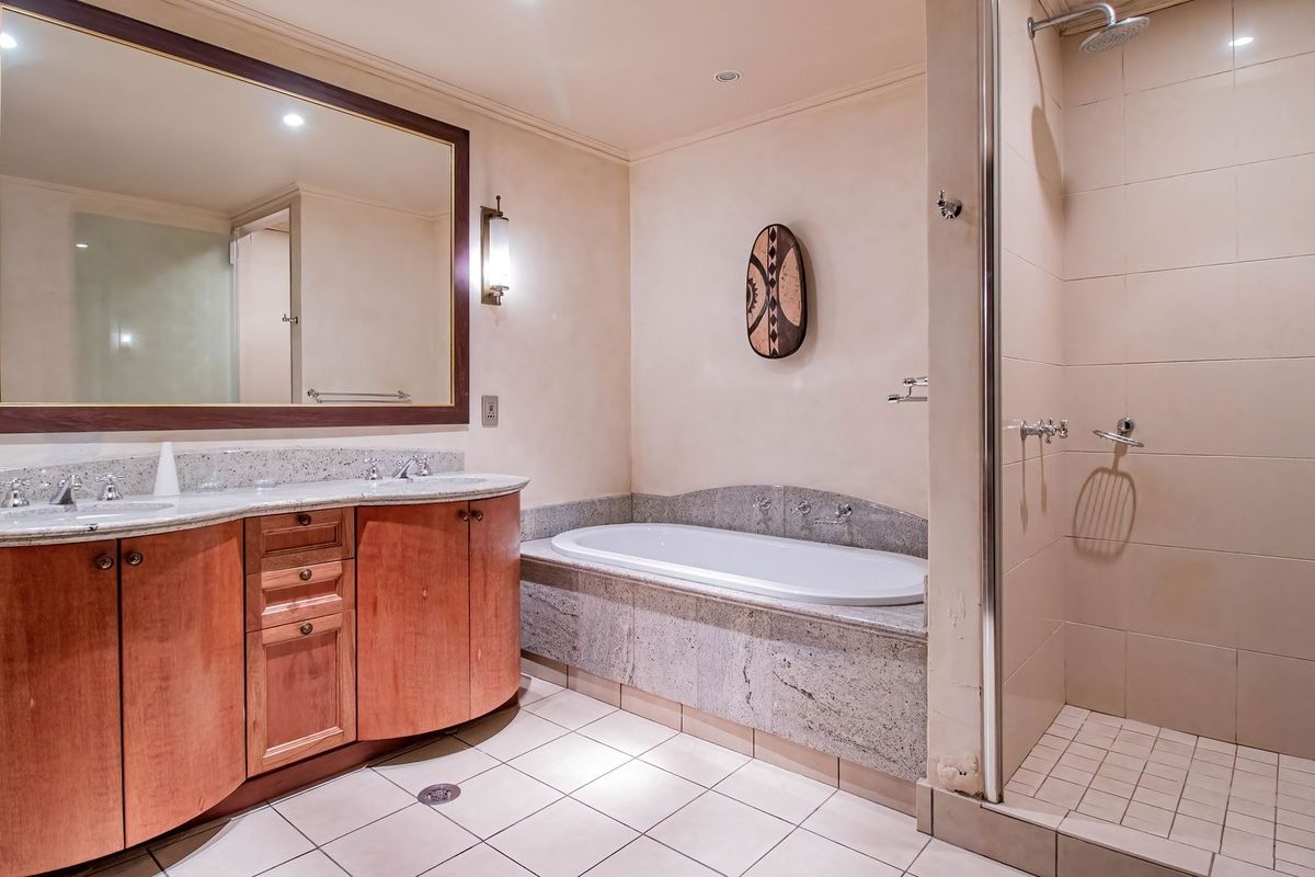 Spacious bathroom featuring a double vanity with granite countertops, a built-in bathtub, and a separate walk-in shower with tiled finishes.