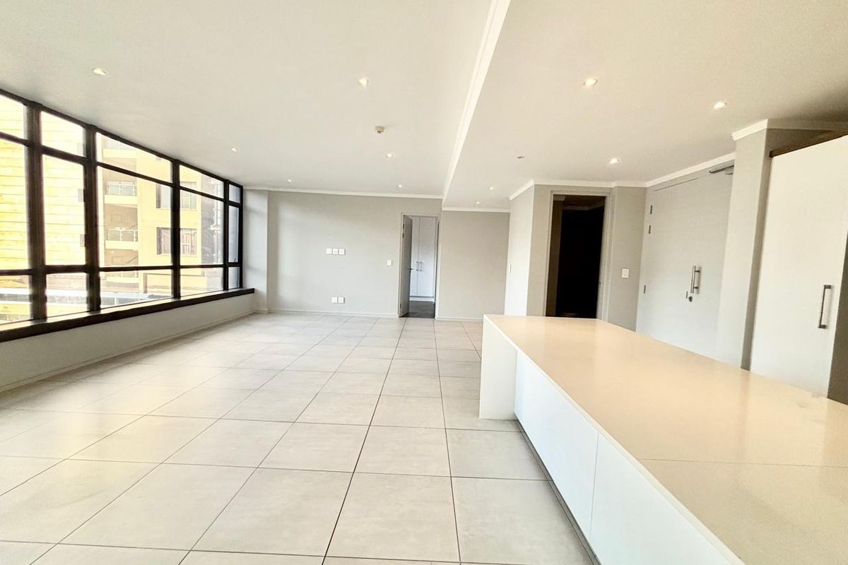 Spacious open-plan living area featuring large windows, modern tiled flooring, recessed lighting, and a sleek built-in kitchen island.