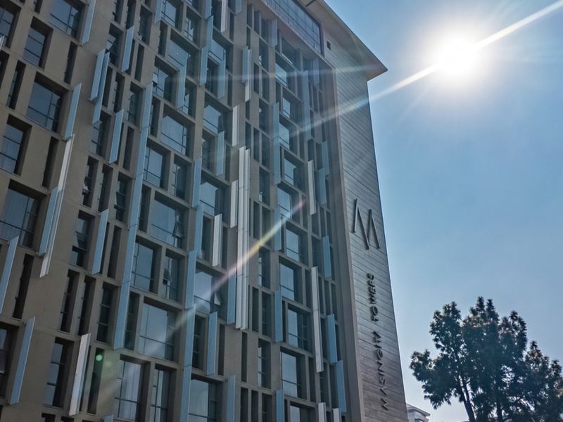 A modern apartment building facade featuring contemporary architectural design with large windows and vertical sun louvres.